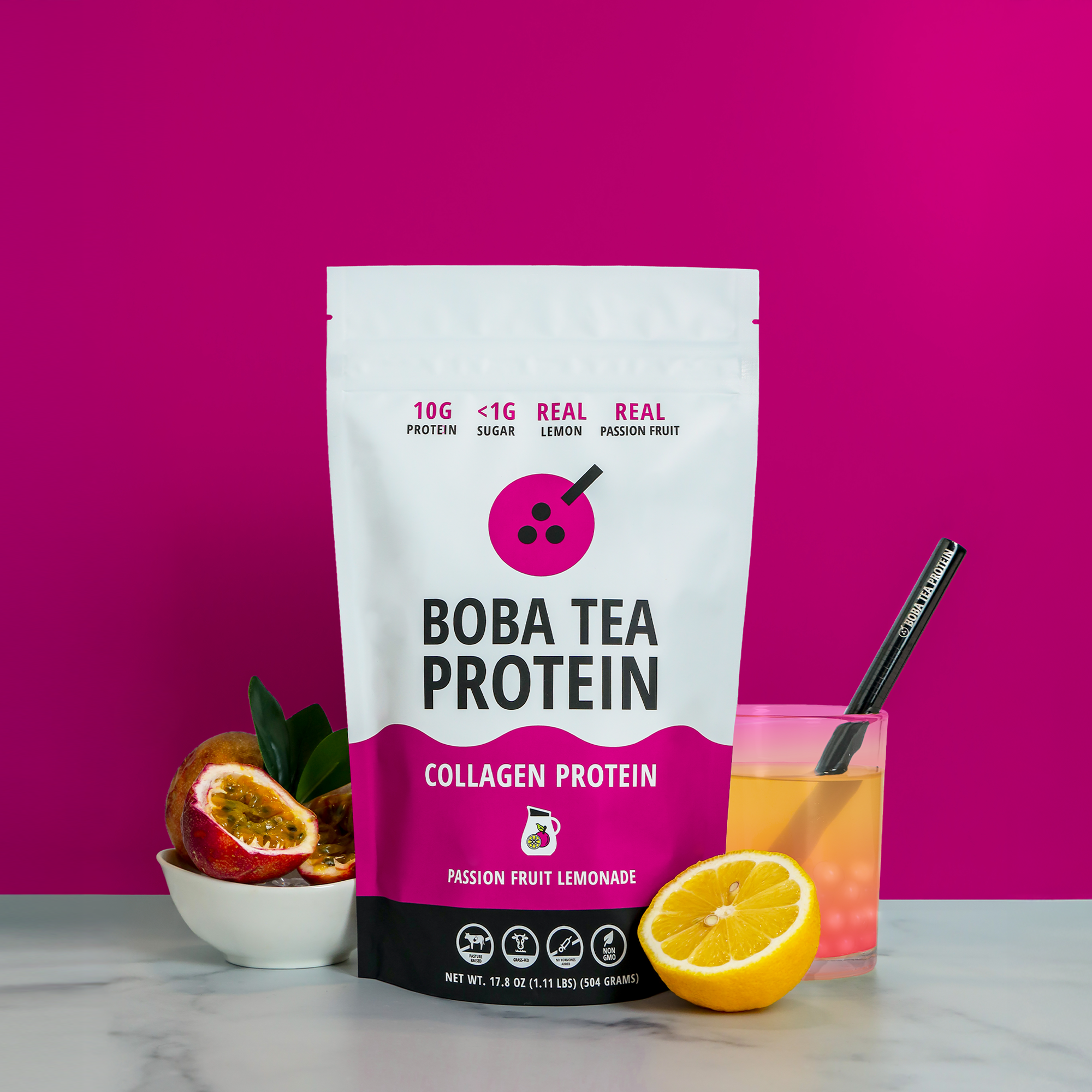 Boba Tea Protein package with a glass of lemonade and passion fruit on a pink background